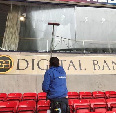 UCS box cleaning Picture of an employee cleaning a window of a box at a football stadium. Ultra Cleaning Service can provide regular maintenance cleaning solutions.
