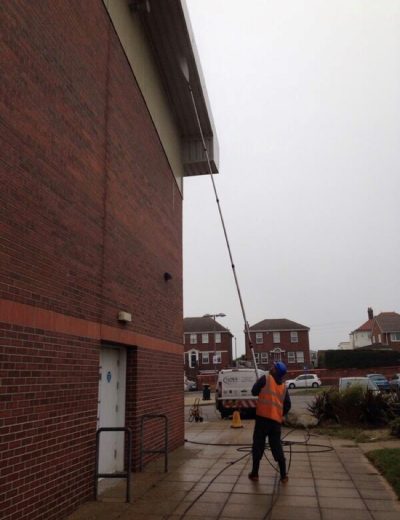 UCS full building clean A picture of a member of the team cleaning a building. Ultra Cleaning Services provide jet washing and soft washing solutions to clean your whole building.