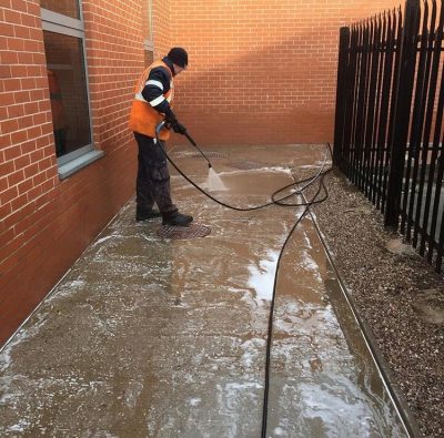 UCS ground cleaning Picture of a member of the Ultra Cleaning Service team power washing a pathway - introducing playground cleaning services.